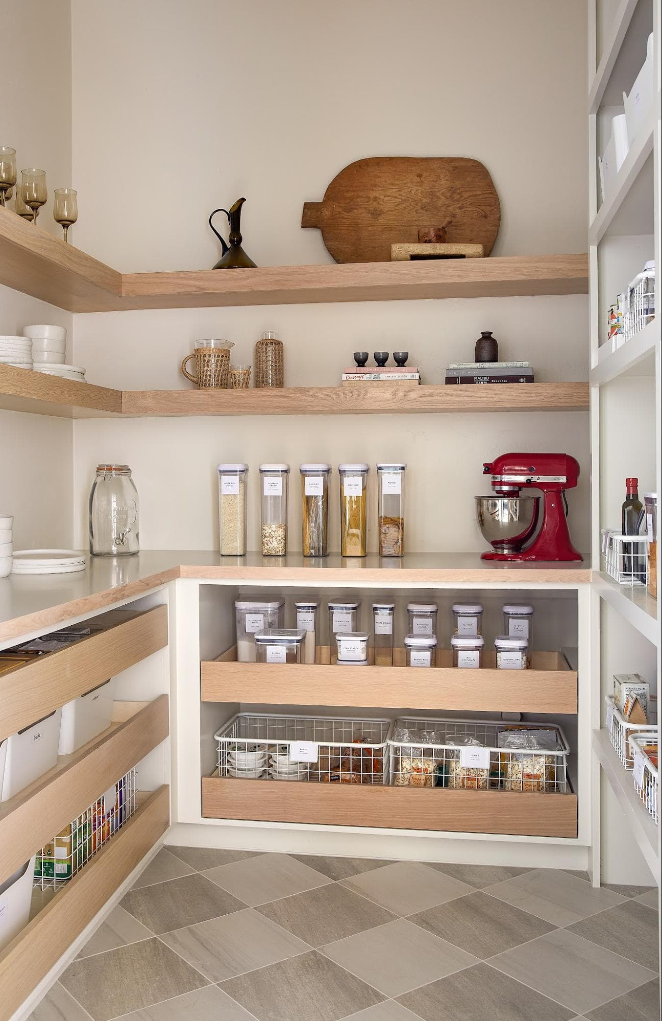 Walk-in pantry with wood shelving, labeled glass jars, and a red stand mixer